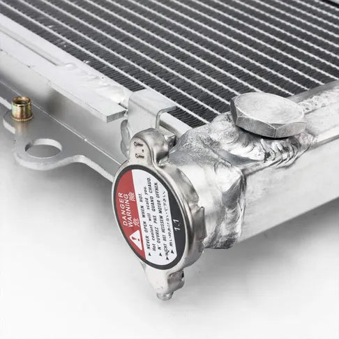 Close-up of a radiator with a warning label on a white background